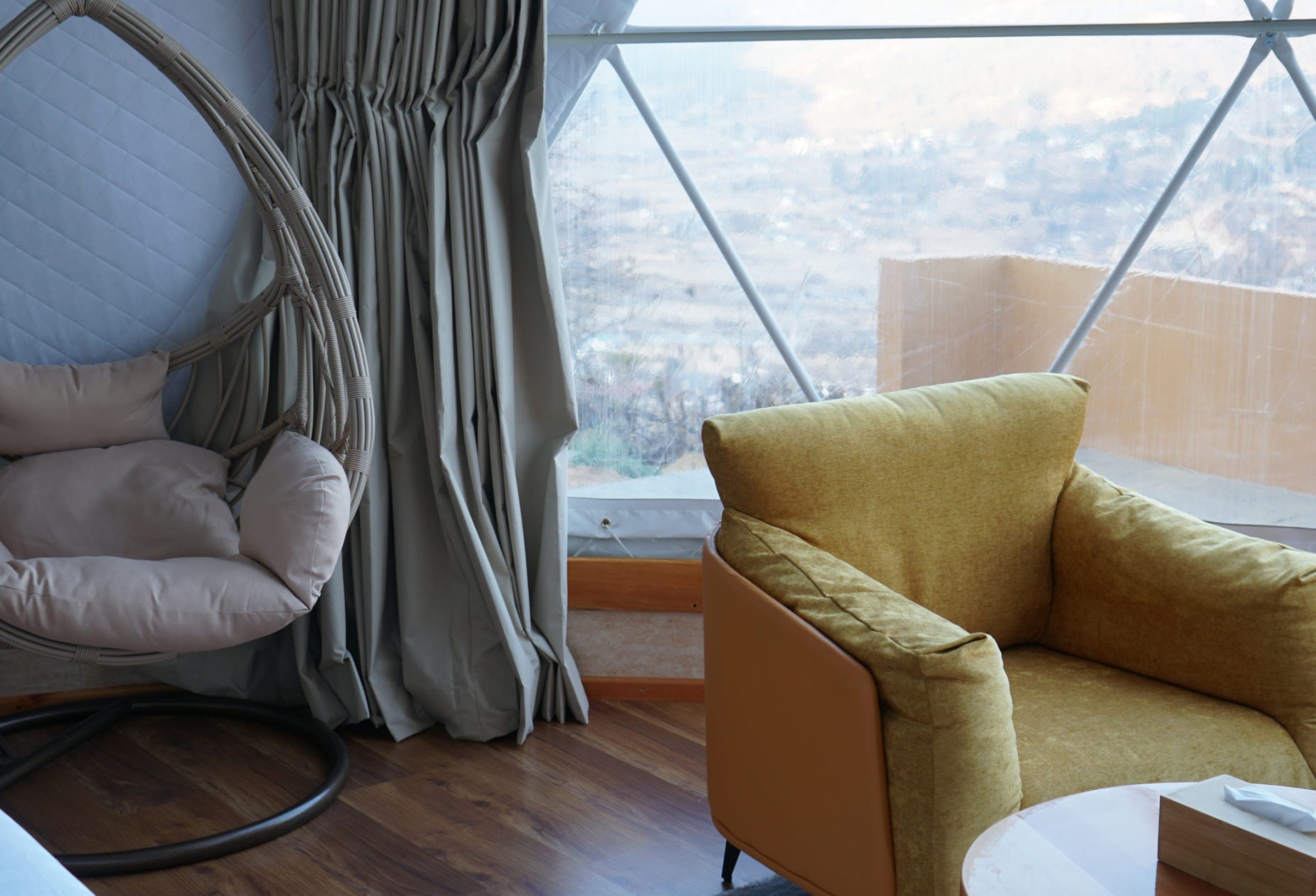 Hanging chair beside the panoramic window in the Hilltop Deluxe Dome