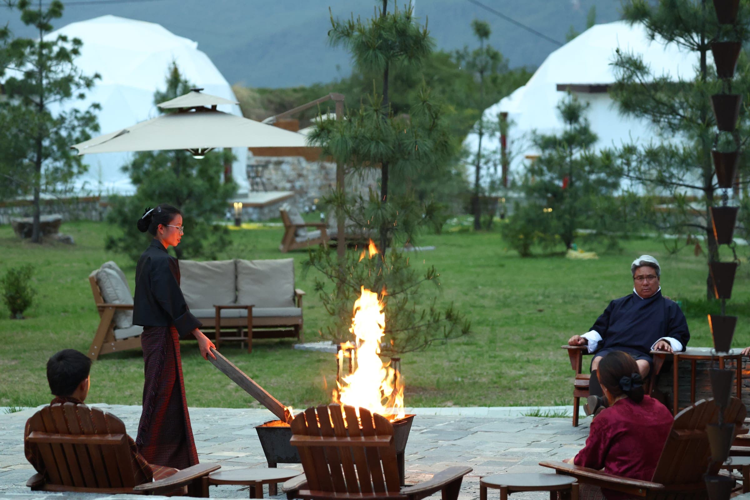 Guests gathered around an evening bonfire beside the riverfront domes