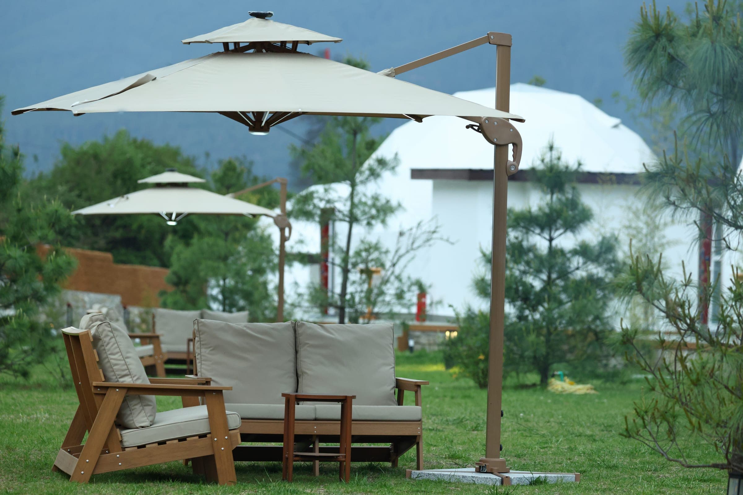 Garden lounge seating with parasols beside a riverfront glamping dome in Kepdinkha, Paro