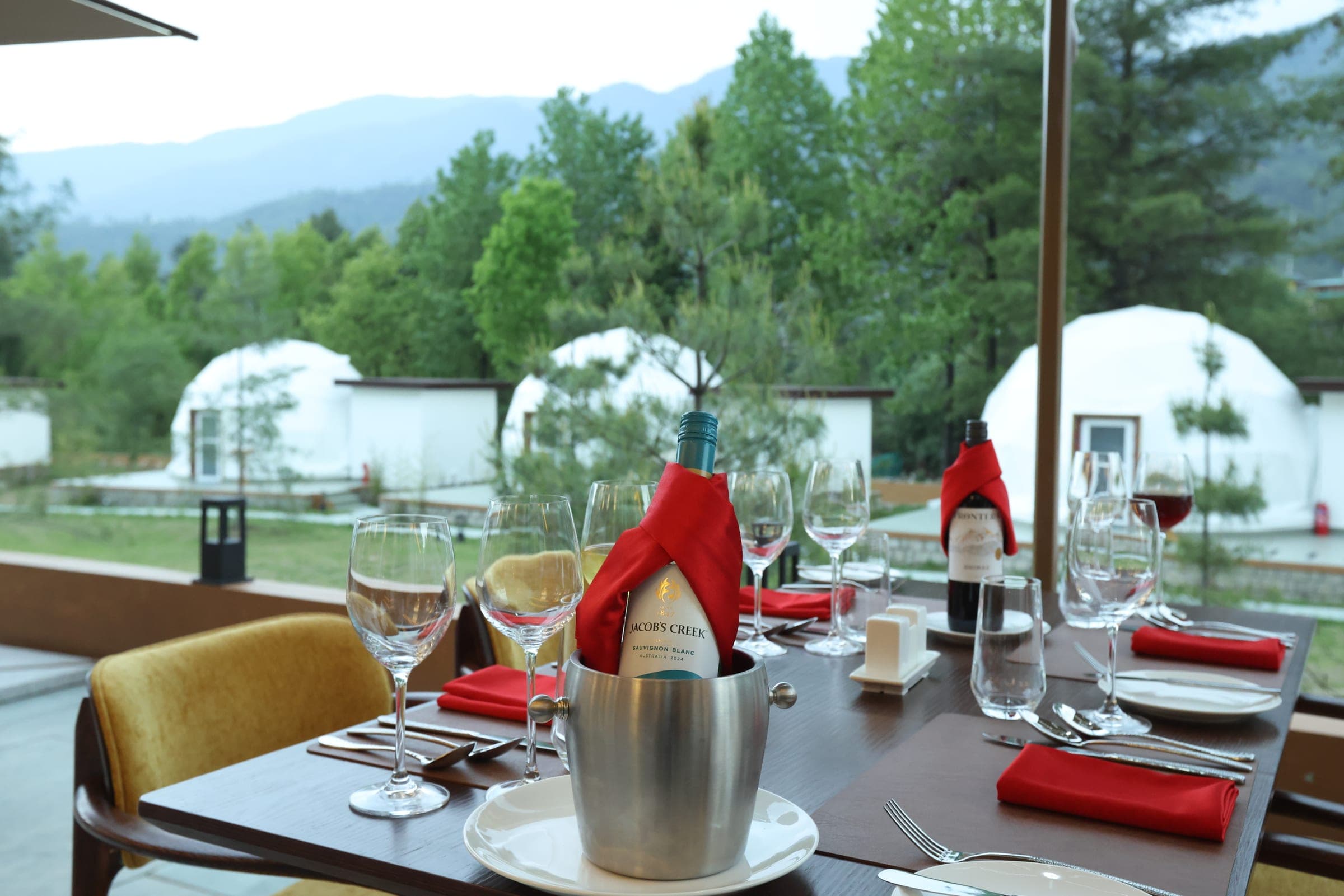 Riverfront dining table set beside the glamping domes at dusk