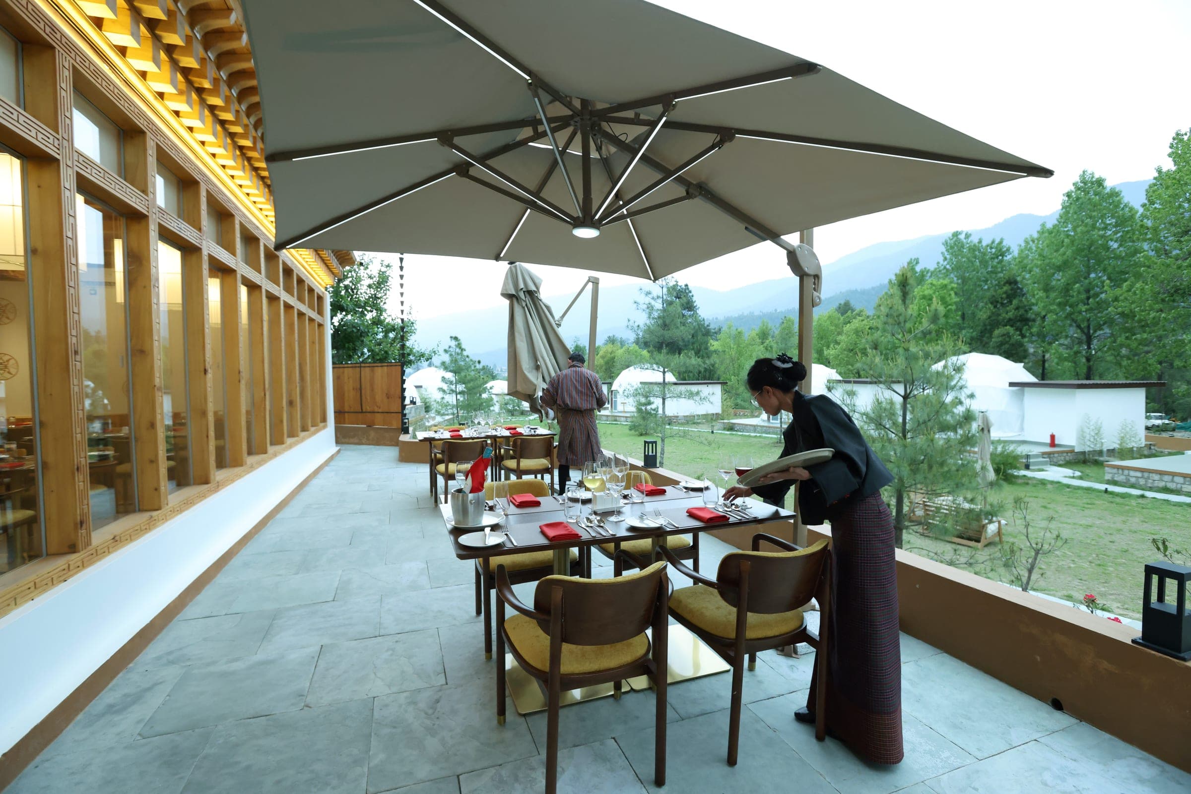 Outdoor terrace dining under umbrellas with mountain views in Paro