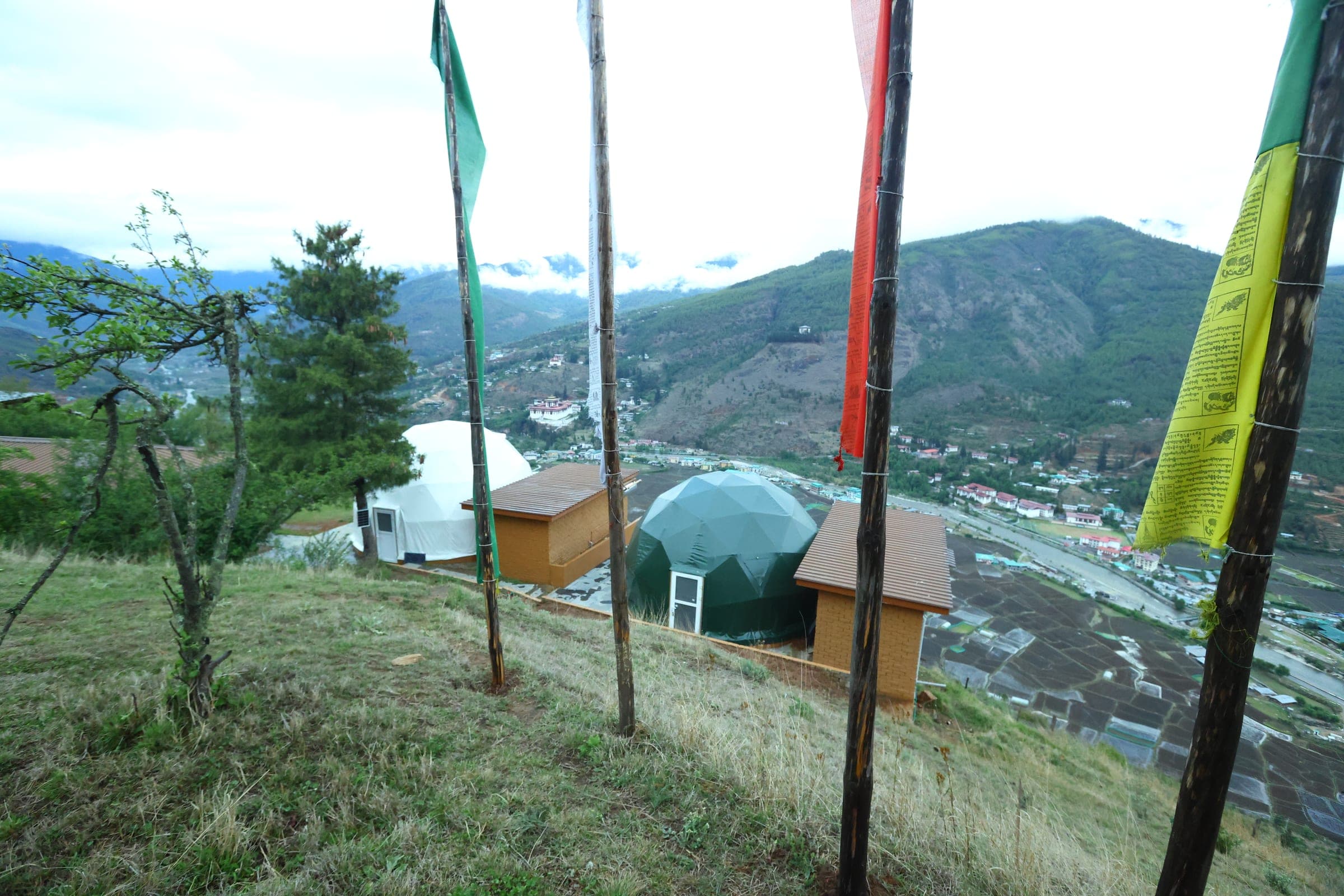 Prayer flags and hilltop domes above the Paro valley at Highland Glamping