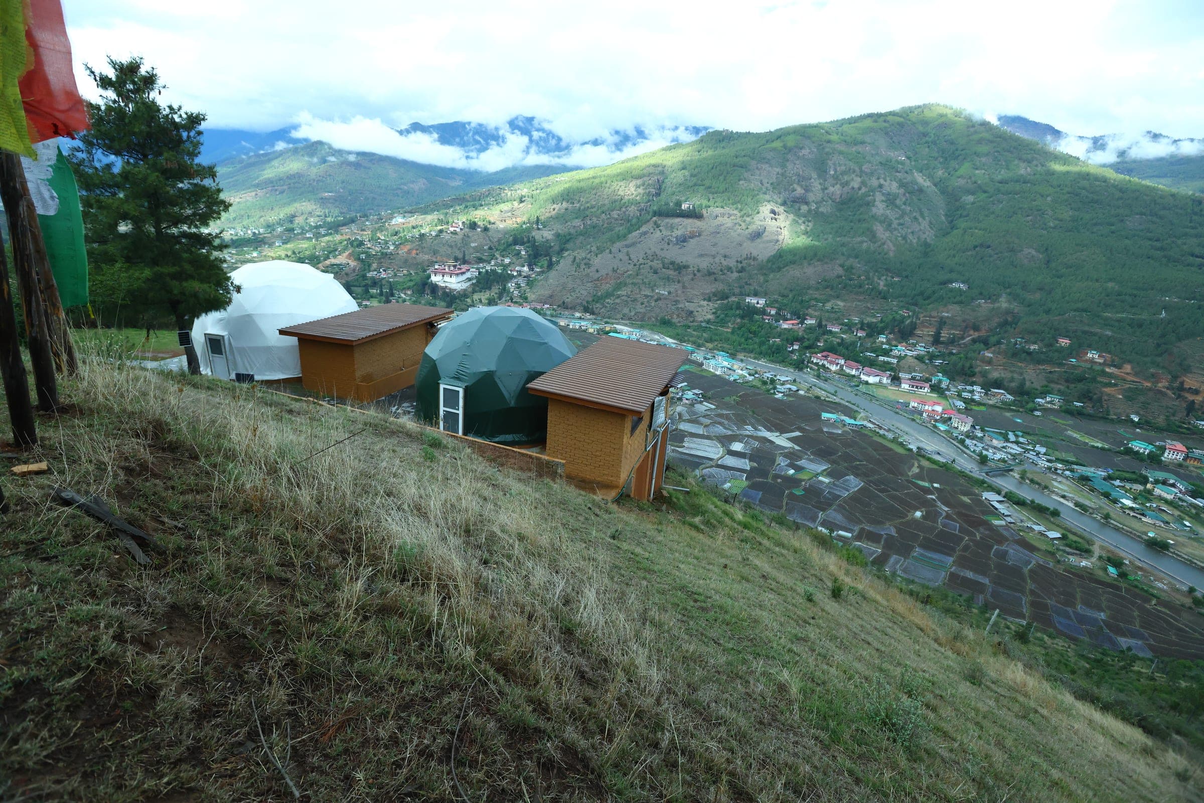 Hilltop glamping domes on a ridge above the Paro valley with Bhutanese prayer flags
